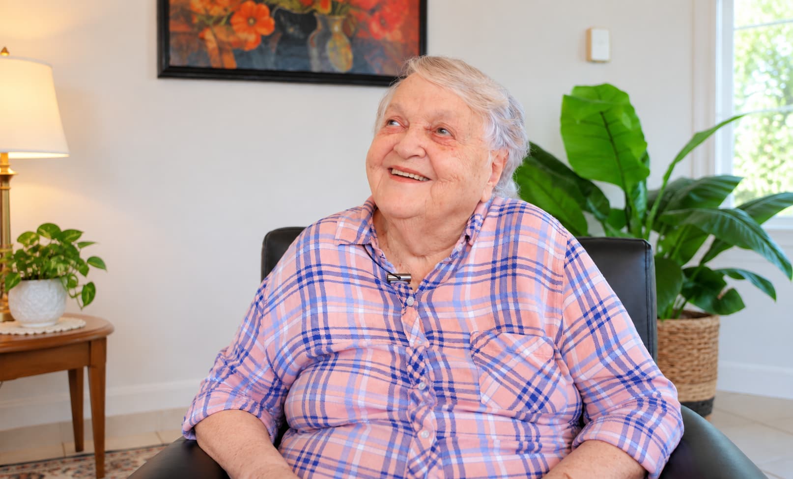 A resident smiling in a sunlit sitting room at Clinton House