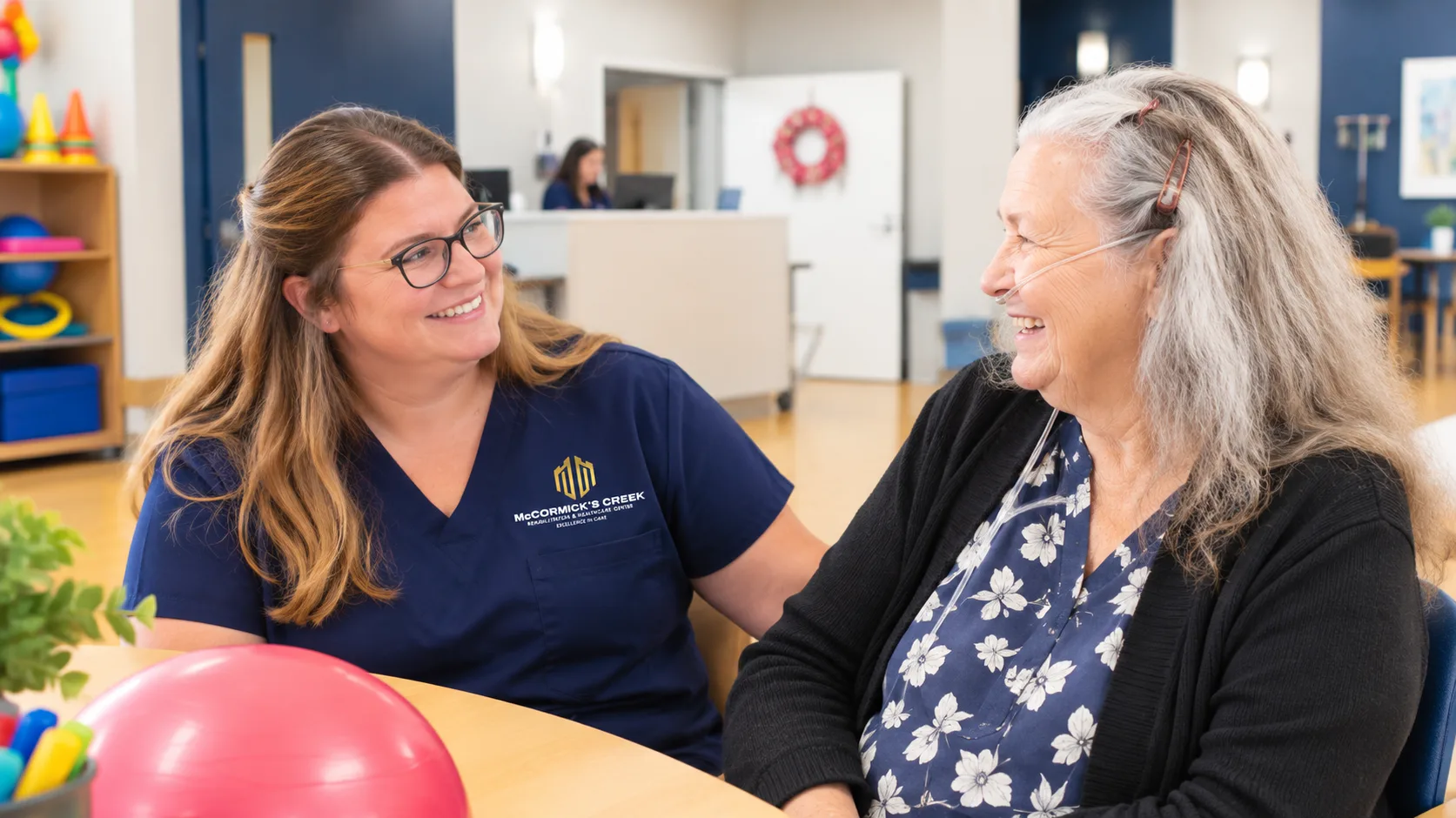 A therapist and a resident working through an exercise with a ball