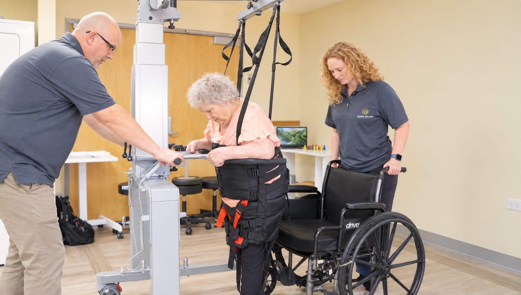 A therapist supporting a resident in a standing frame