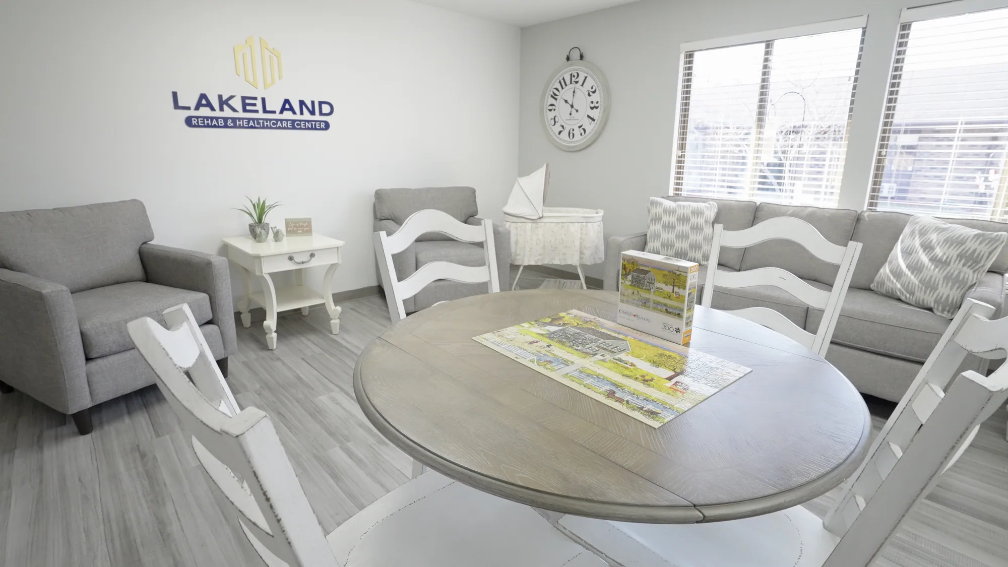 A sitting room at Lakeland with a round table and sofas beneath the Lakeland sign