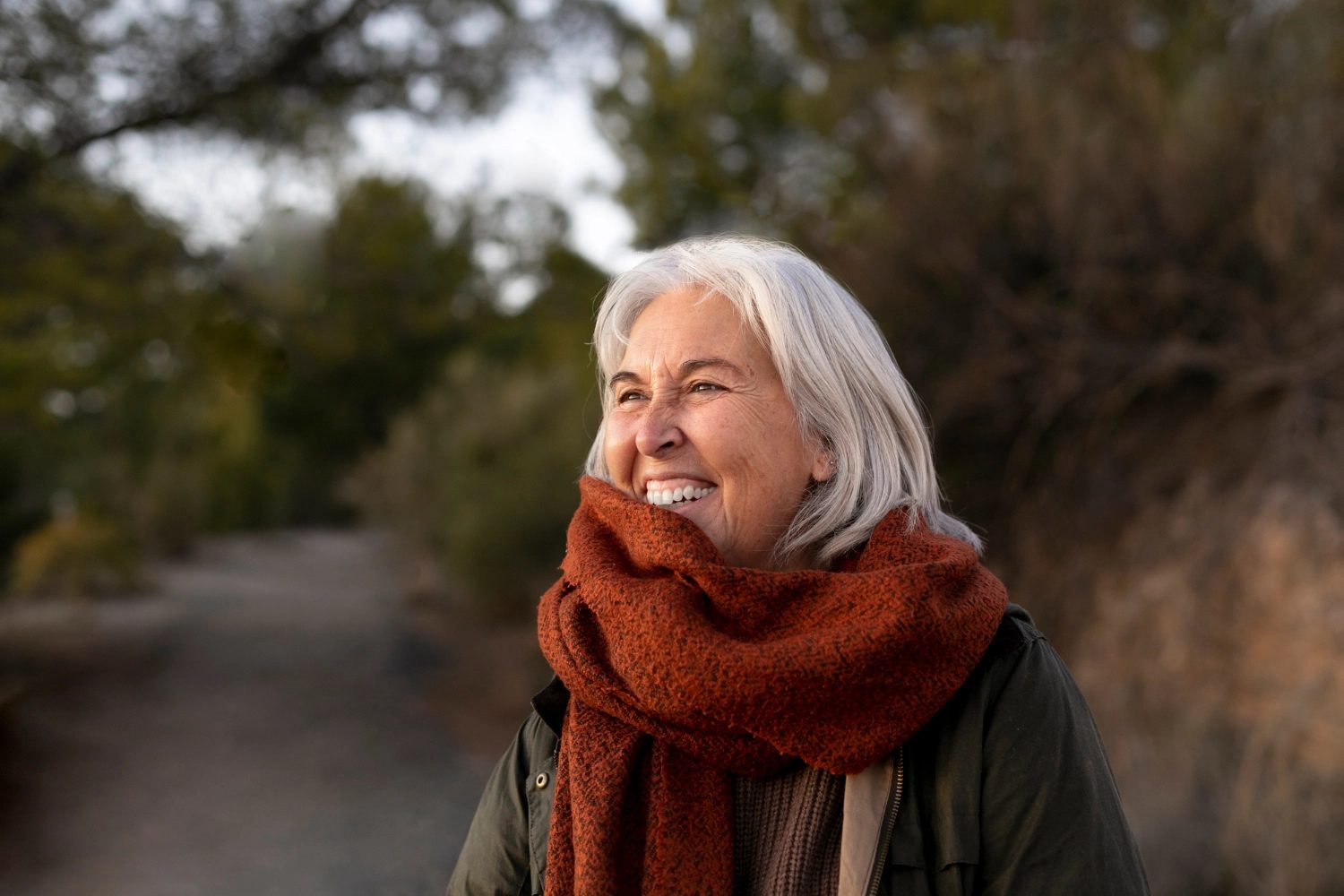 A resident laughing outdoors in a warm red scarf